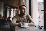 Pensive young man resting in cafe during coffee break