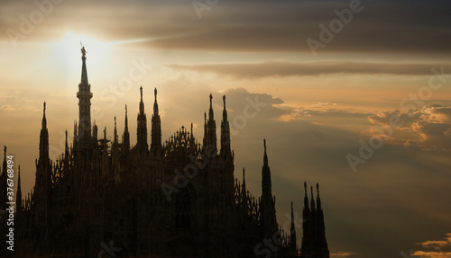 Silhouette of the statue of the Madonna (la Madonnina) on the highest spire of the Milan Cathedral at sunset, Italy photo