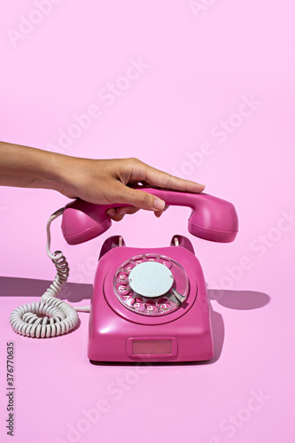 Layout made of pink telephone on blue background. Retro vintage 60's and 70's aesthetic with summer shadows. Flat lay.