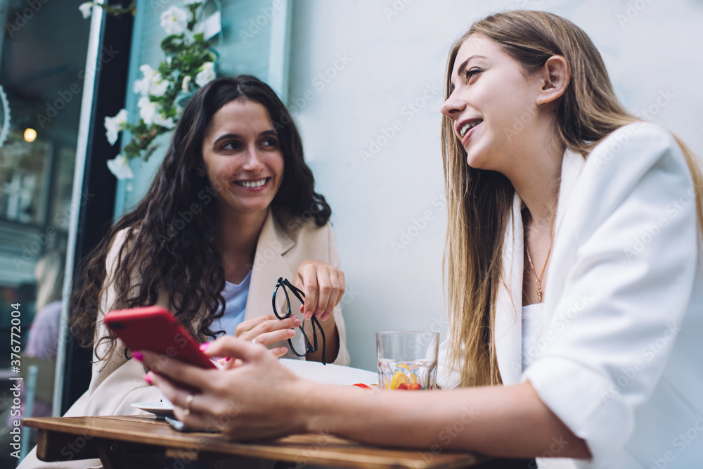 Happy women sharing news in outdoor cafe Happy women sharing news in outdoor cafe