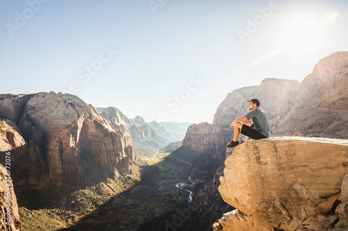 Man hiking Angels landing trail, sitting on rock, Zion National Park, Utah, USA