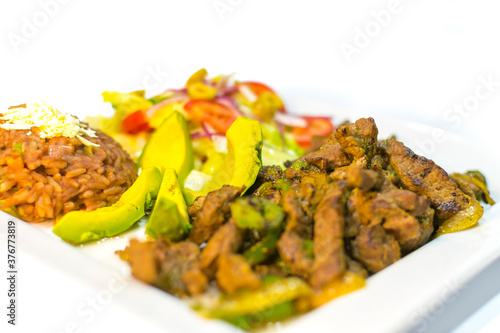 plate with meat, beans, avocado and tortillas toasted in squares to eat with beer and lemon. lovely black background.