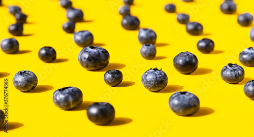 Creative pattern made of blueberries on pastel yellow background. Berries minimal concept.