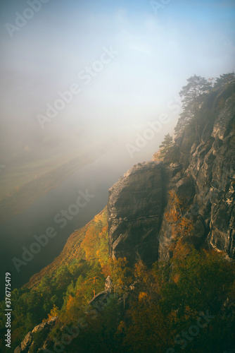 beautiful mystical and picturesque view of the rocks near the river in autumn with soft sunlight through the clouds