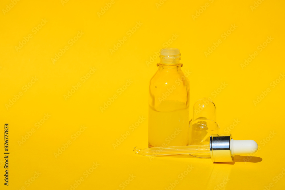 Yellow serum liquid oil in clear bottle with dropper on orange background. Organic SPA cosmetics with herbal ingredients. Citrus essential oil, cosmetics aromatherapy. Flat lay. Copy space.