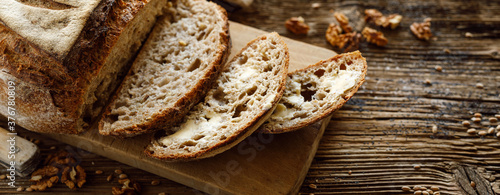 Traditional sourdough bread sliced smeared with butter baked in a craft bakery on a wooden table close up,