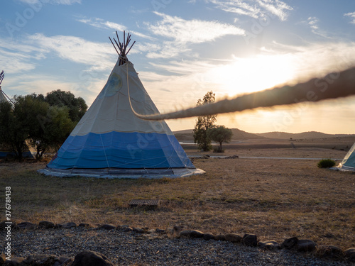 Caseta de campa  a de estilo tipi indio en un bosque durante la puesta de sol