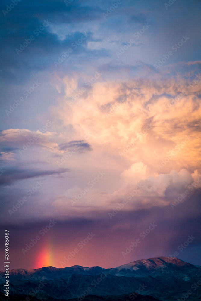 View of storm clouds with rainbow over mountain View of storm clouds with rainbow over mountain