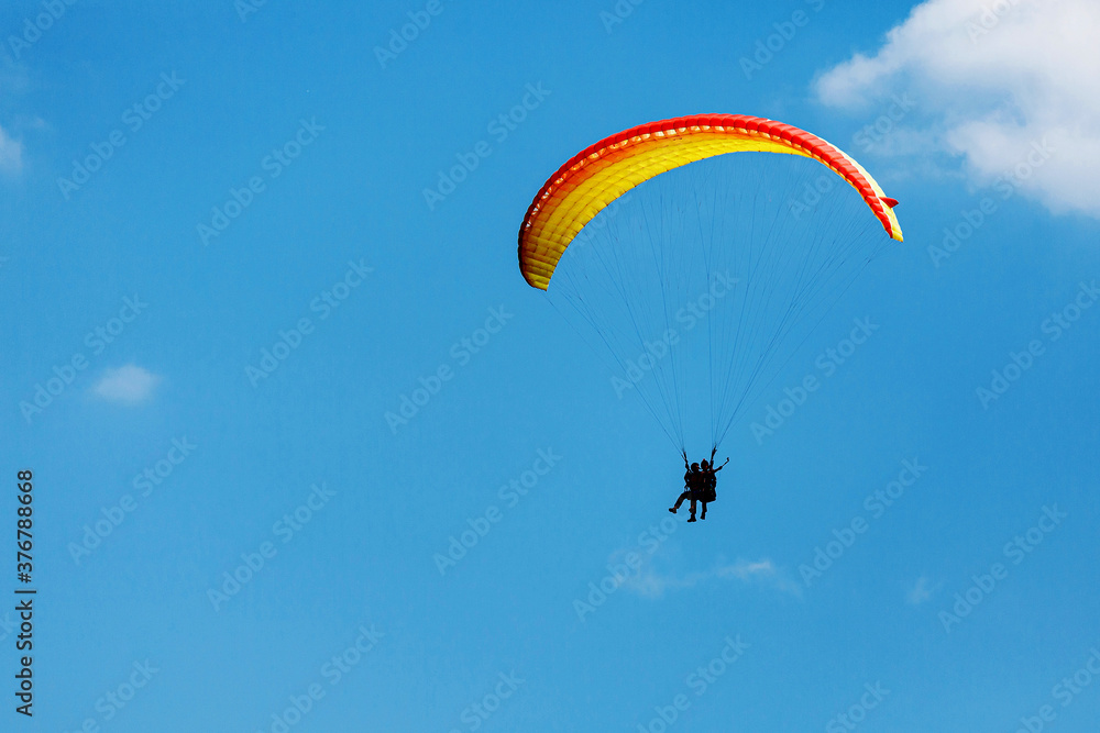 Yellow Paraglider tandem instructor with a tourist flying into the sky with clouds on a sunny day. making a selfie Yellow Paraglider tandem instructor with a tourist flying into the sky with clouds on a sunny day. making a selfie