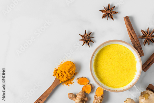 Turmeric drink, latte, tea, golden milk with cinnamon, ginger and anise in a mug on white background. top view
