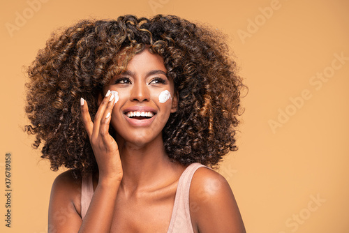 Beautiful african girl applying a cream on cheek.