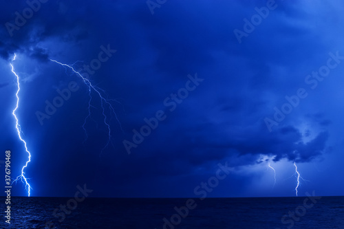 A few lightning bolts over the sea at dark night
