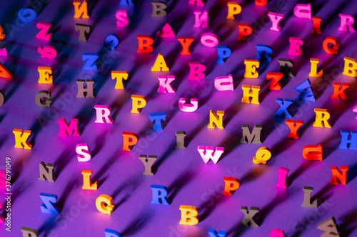 The letters of the alphabet in random order. Latin letters stand on a lilac background. The concept of reading books and literacy. Background of Latin letters, blurred closer to the edges.