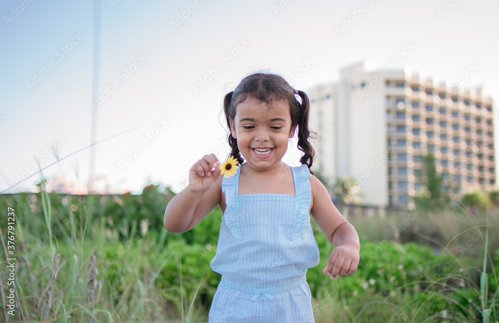 Little girl playing with flowers on the beach Little girl playing with flowers on the beach