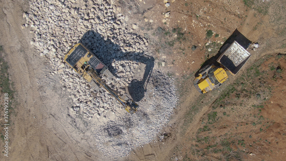 TOP DOWN: Industrial excavator crushing rocks and turning them into gravel.
