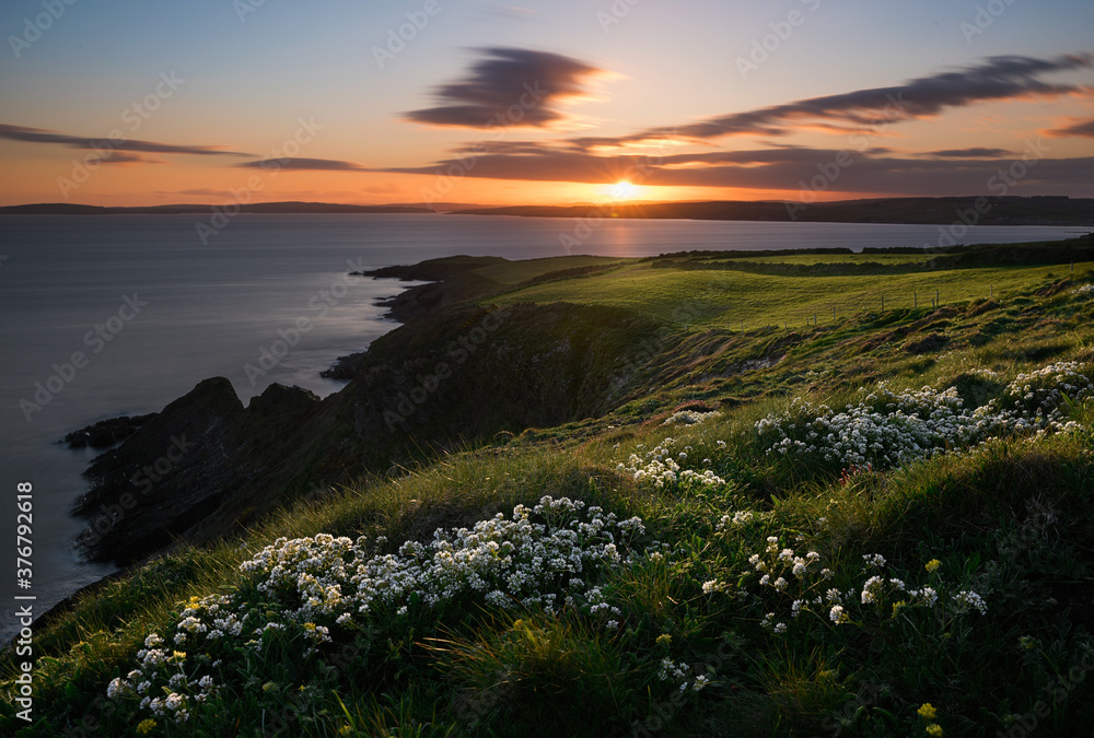 Scenic view of coast against cloudy sky during sunset