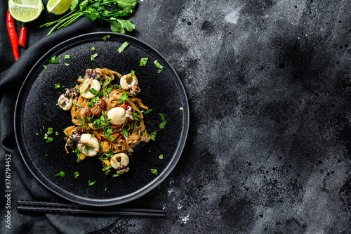 Asian stir fry Noodles with cuttlefish and vegetables. Black background. Top view. Copy space