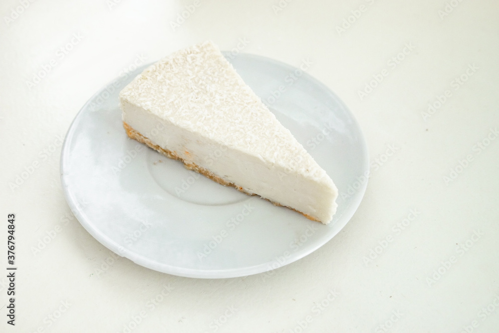 1 piece of cheesecake on a white saucer on a white table on a white kitchen with natural light