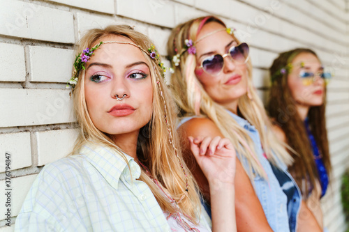 Three beautiful caucasian women standing by white brick wall - Sisters or girl friends with mother in summer day looking to the side - real people leisure activity youth carefree concept close up