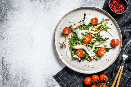 Salad with chicken, arugula, walnuts, tomatoes and Parmesan. gray background. Top view. Copy space