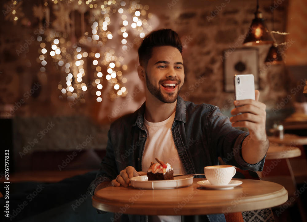 Young blogger taking selfie at table in cafe