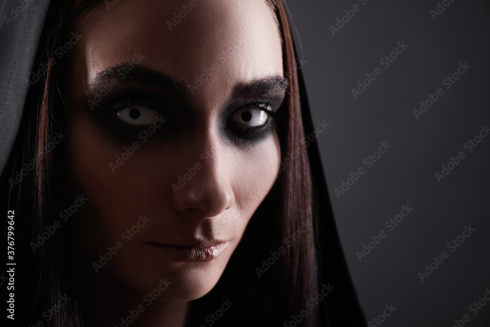 Mysterious witch with spooky eyes on black background, closeup Mysterious witch with spooky eyes on black background, closeup