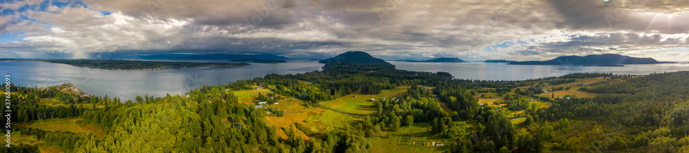 Aerial Panorama of Lummi island, Washington. Sunset and a rainbow over the city of Bellingham while highlighting the middle of Lummi Island in the San Juan Island archipelago.