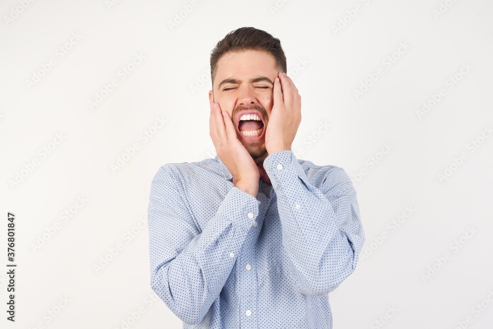 Doleful desperate crying European man dressed in formal shirt and bow tie poses against white background being in depression after quarrel , looks stressfully, frowns face, . feels lonely and anxious Doleful desperate crying European man dressed in formal shirt and bow tie poses against white background being in depression after quarrel , looks stressfully, frowns face, . feels lonely and anxious