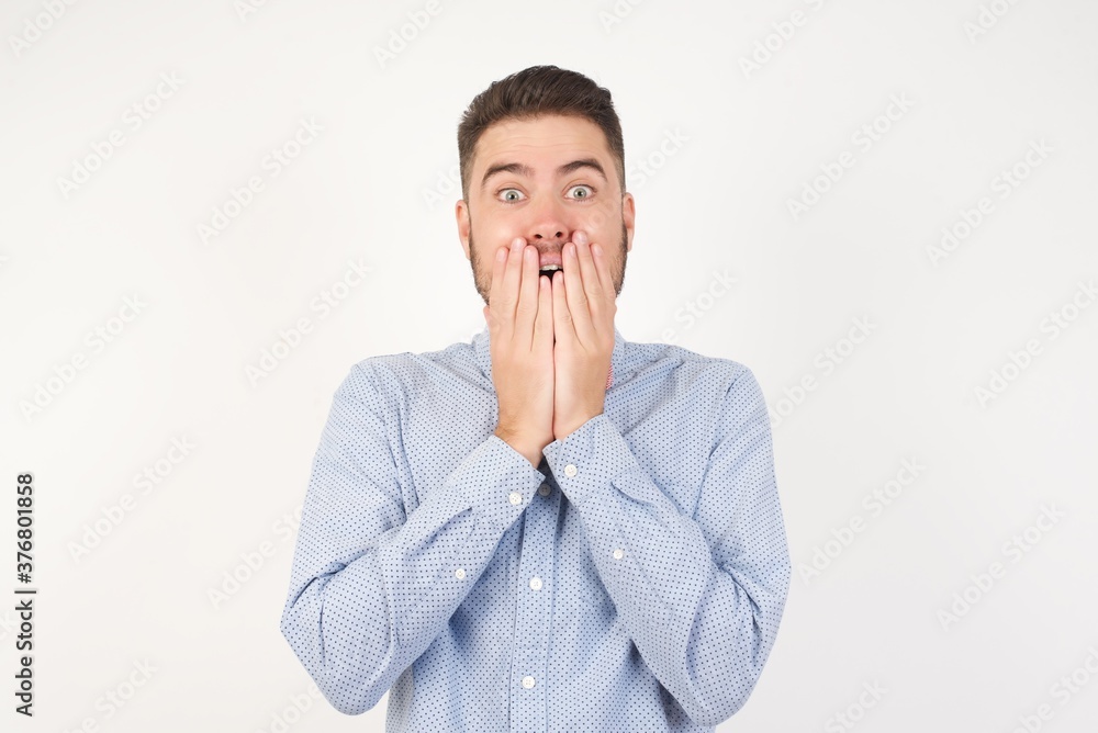 Vivacious European man dressed in formal shirt and bow tie poses against white background giggles joyfully, covers mouth, has fun alone, has natural laughter, hears positive story or funny anecdote Vivacious European man dressed in formal shirt and bow tie poses against white background giggles joyfully, covers mouth, has fun alone, has natural laughter, hears positive story or funny anecdote