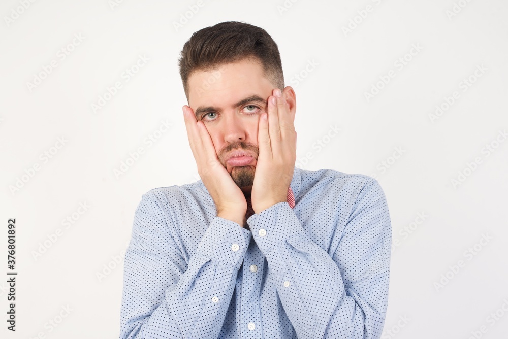 European man dressed in formal shirt and bow tie poses against white background. Tired hands covering face, depression and sadness, upset and irritated for problem European man dressed in formal shirt and bow tie poses against white background. Tired hands covering face, depression and sadness, upset and irritated for problem