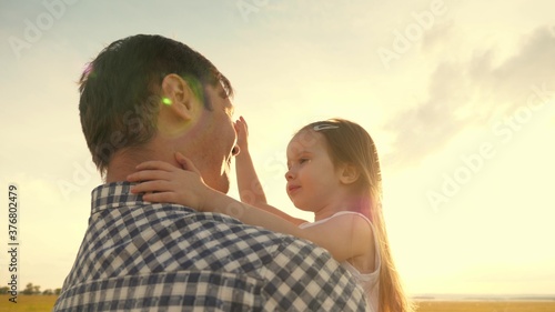 Dad hugs happy little daughter in summer park. Father and little child play together, laugh and hug. happy family travel. healthy baby in arms of father. Dad is off. Happy family and childhood concept