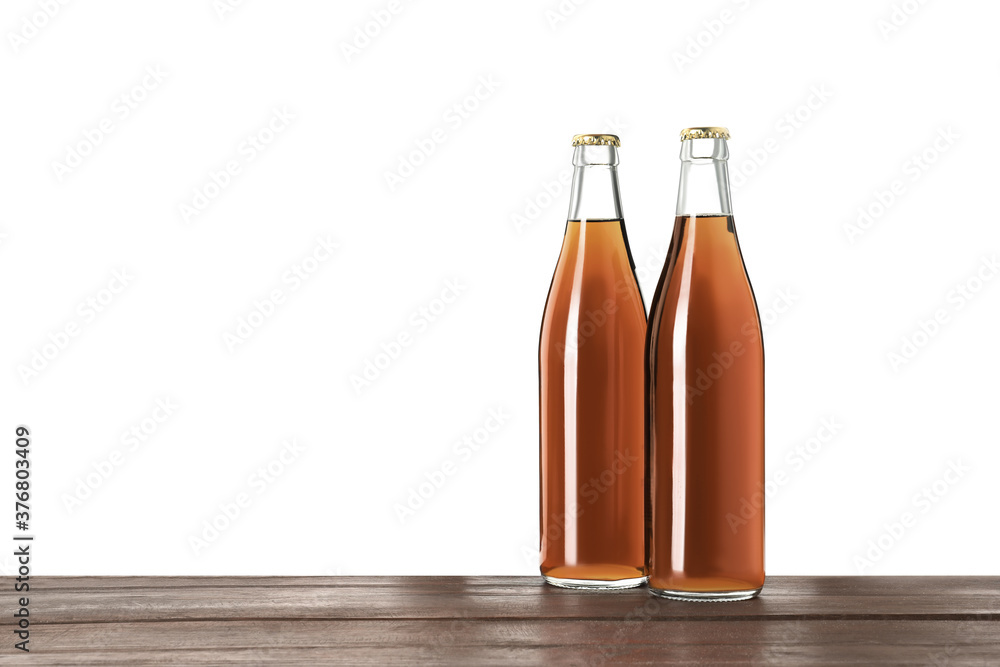 Bottles of delicious kvass on wooden table against white background Bottles of delicious kvass on wooden table against white background