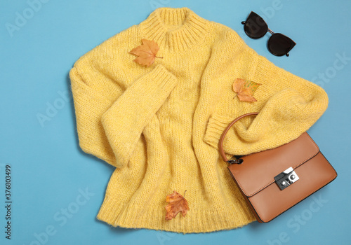 Flat lay composition with sweater and dry leaves on light blue background. Autumn season