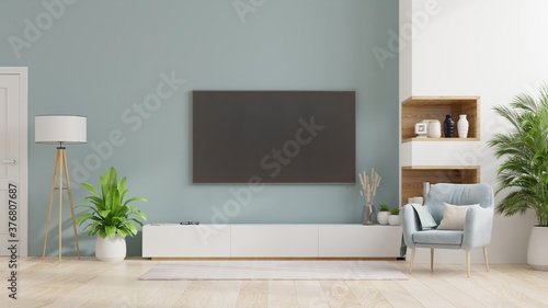 TV on cabinet in modern living room Interior of a bright living room with armchair on empty blue wall background.