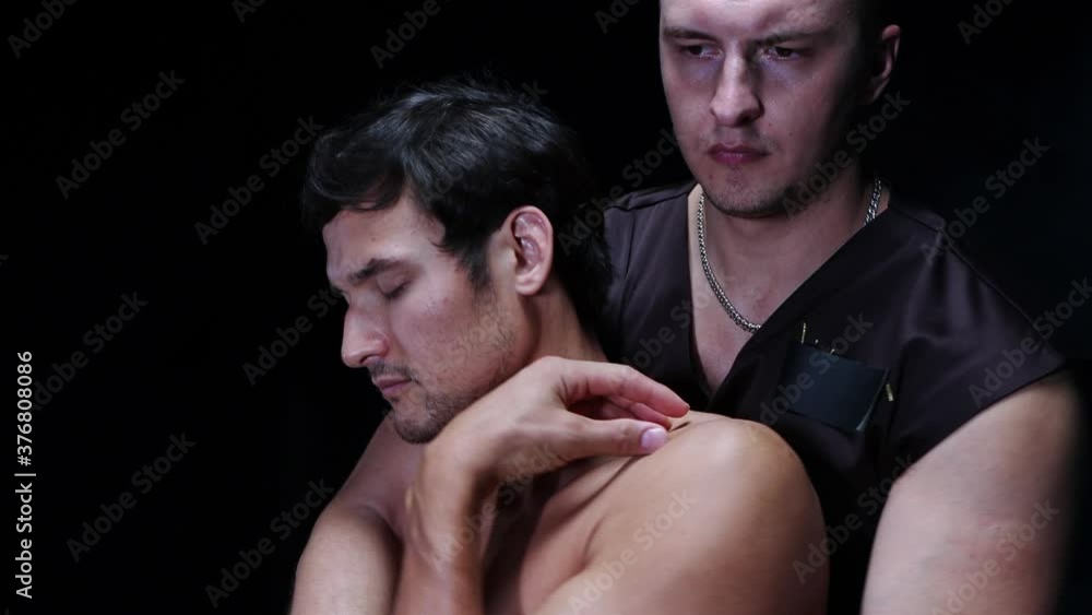 Chiropractic therapy in the studio - the client sitting on the couch and the therapist pressing his hands towards his body Chiropractic therapy in the studio - the client sitting on the couch and the therapist pressing his hands towards his body