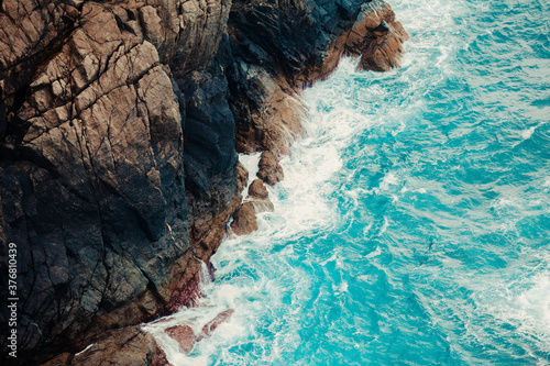 Foto Aerial shot of the crystal water sea touching the rocks of the bottom of a mount