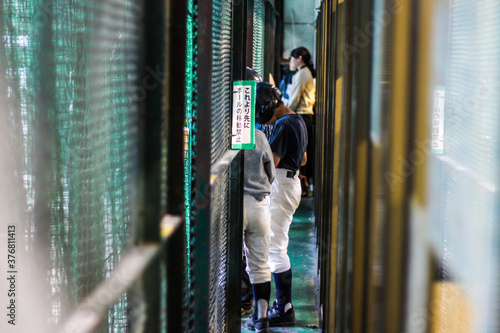 Japanese people waiting in line at a batting cage