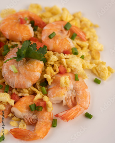 Stir fried eggs with shrimp on a white plate.