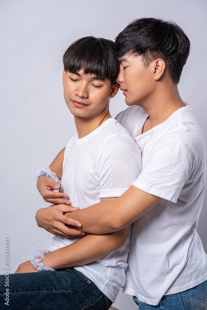 Two men who love each other hug from behind another. Two men who love each other hug from behind another.