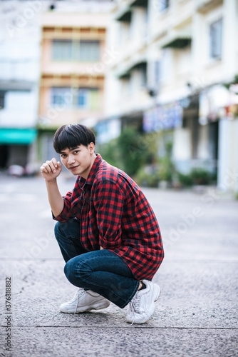 A young man in a striped shirt sitting on the street