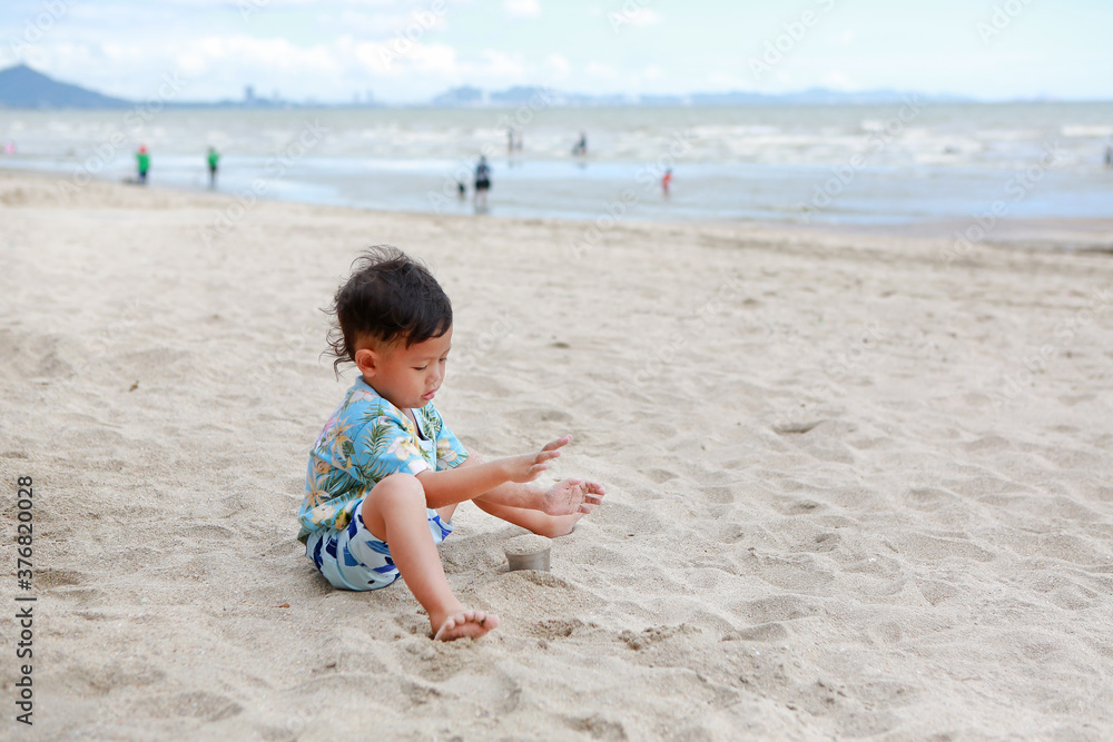 Portrait of little asian baby boy having fun with sand at the beach. Portrait of little asian baby boy having fun with sand at the beach.