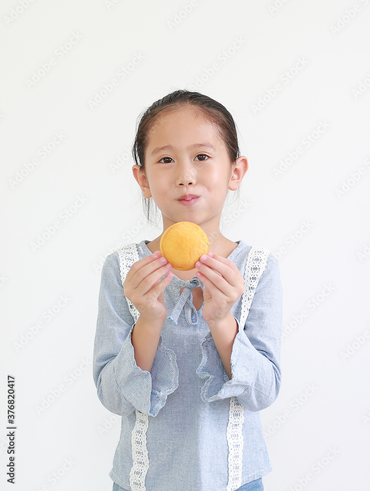 Portrait of happy asian little child girl hold and eating Custard Cake isolated on white background. Portrait of happy asian little child girl hold and eating Custard Cake isolated on white background.