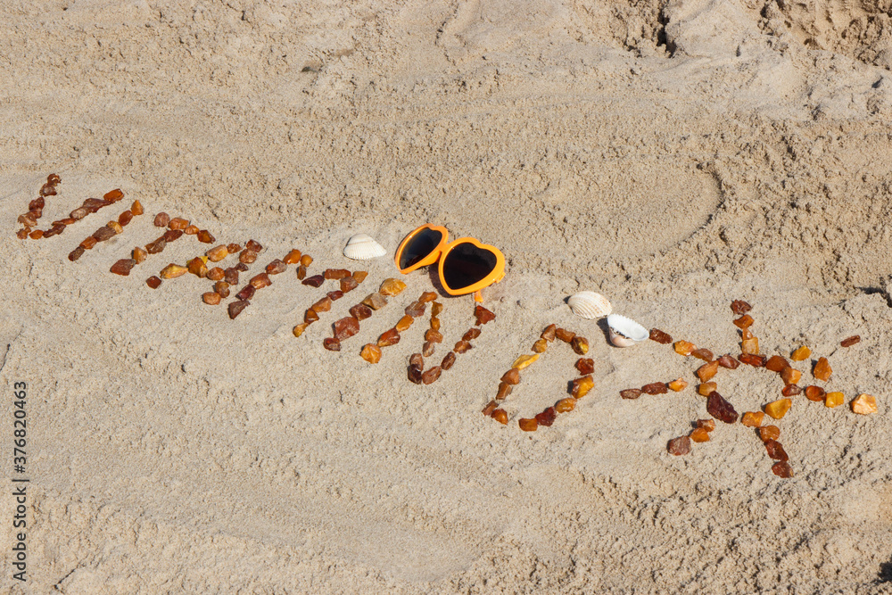 Obraz premium Inscription vitamin D with shape of sun and sunglasses on sand at beach. Prevention of vitamin D deficiency