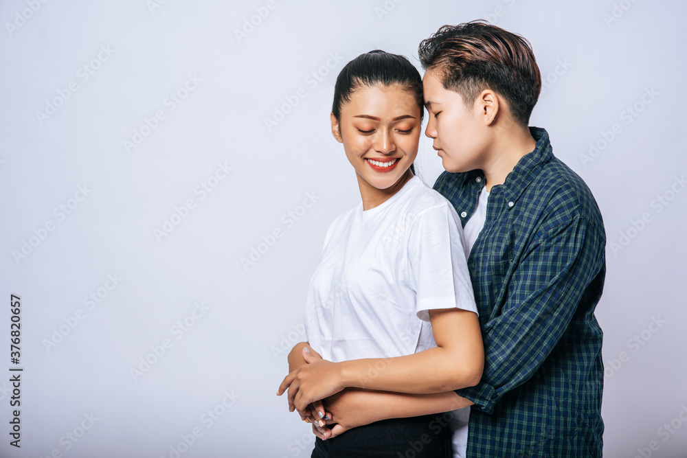 Two female lovers standing and hugging from behind. Two female lovers standing and hugging from behind.