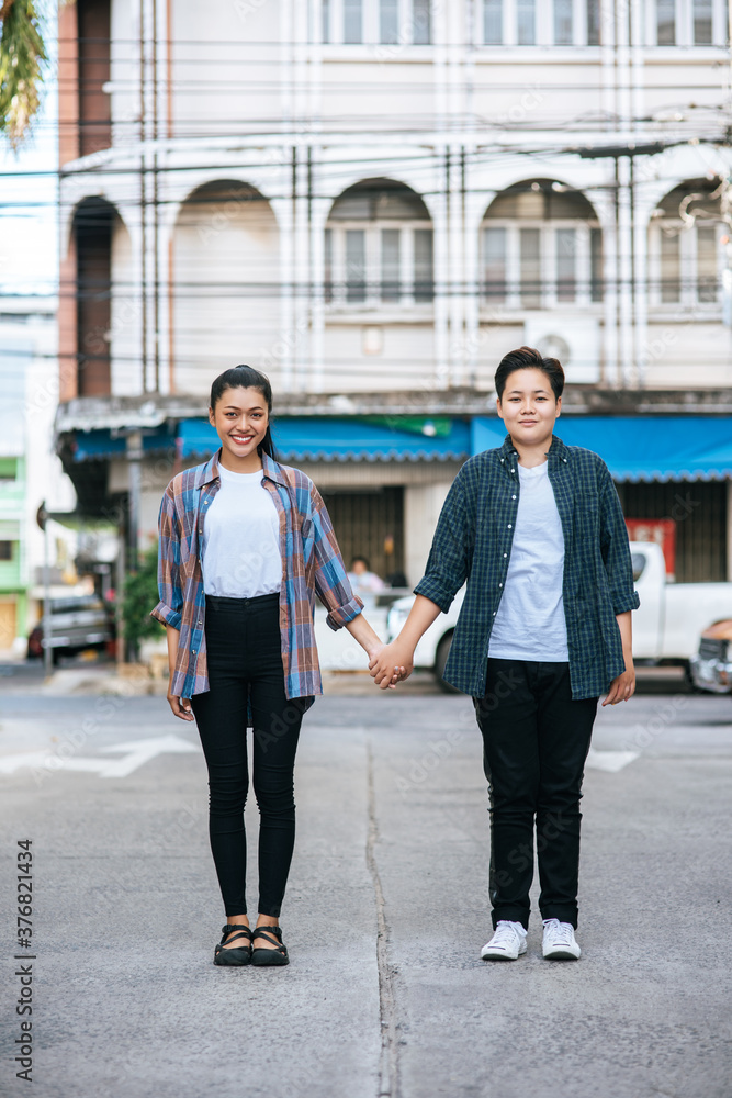 Two loving women standing and holding hands on the street. Two loving women standing and holding hands on the street.