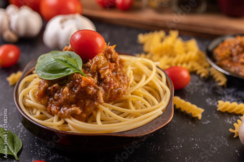 Spaghetti saute in a gray plate with tomatoes and basil