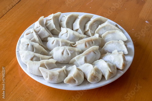 A plate of freshly wrapped raw dumplings, traditional Chinese food