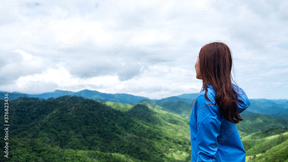 Naklejka premium Portrait image of female traveler looking at a beautiful green mountains view