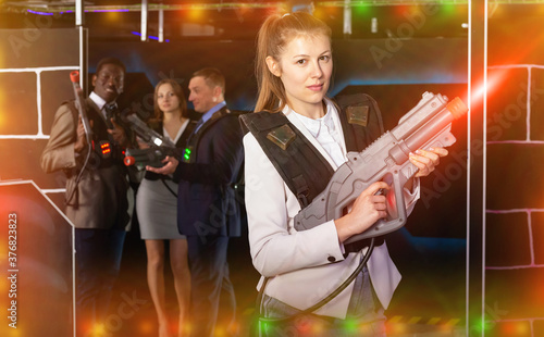 Emotional portrait of woman playing laser tag with her co-workers in dark room © JackF
