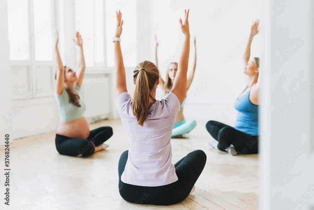 © Galina Zhigalova - Group of pregnant women in sports uniforms with coach doing gymnastic in the bright studio © Galina Zhigalova - Group of pregnant women in sports uniforms with coach doing gymnastic in the bright studio